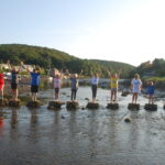 young people standing on stones across the river in Lerryn