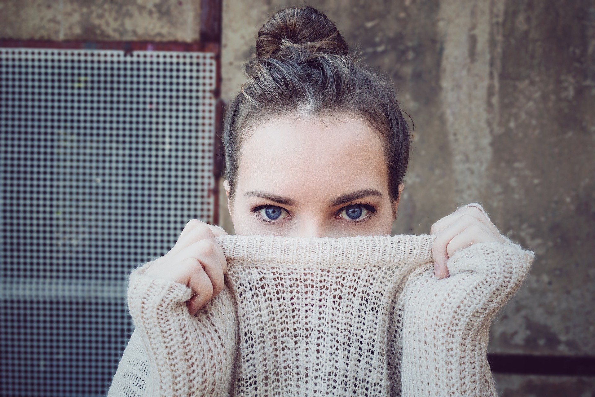 Woman hiding behind her jumper