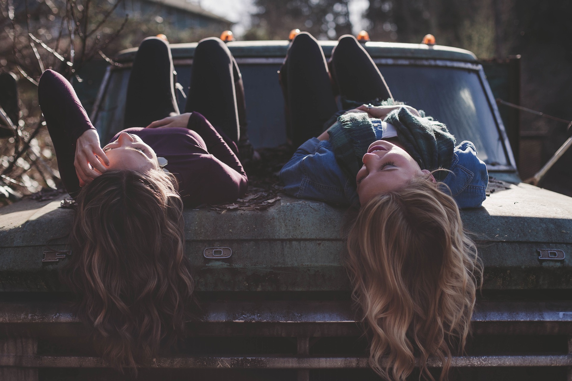 two girls lying on a car and chatting