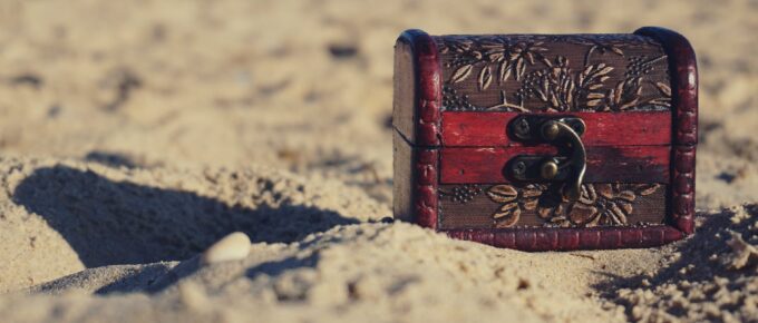 red and black wooden chest on white sand