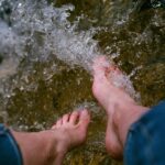 person washing feet in stream