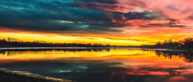 body of water under by cirrus clouds during golden hour