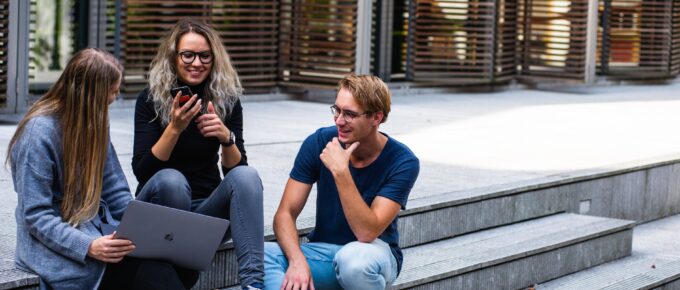 three persons sitting on the stairs talking with each other