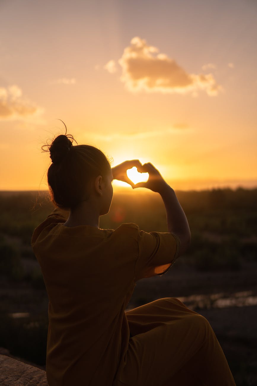 woman sitting while showing heart sign hands