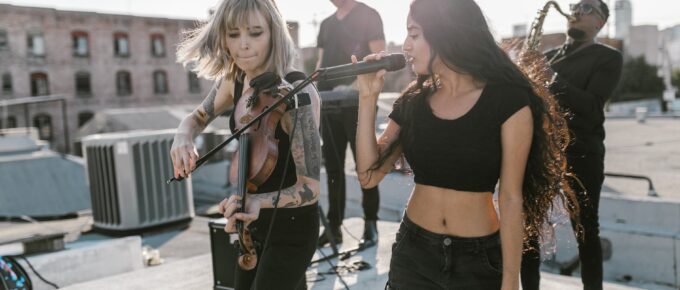 woman in black top singing beside woman playing violin