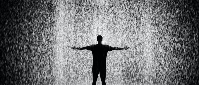 silhouette and grayscale photography of man standing under the rain