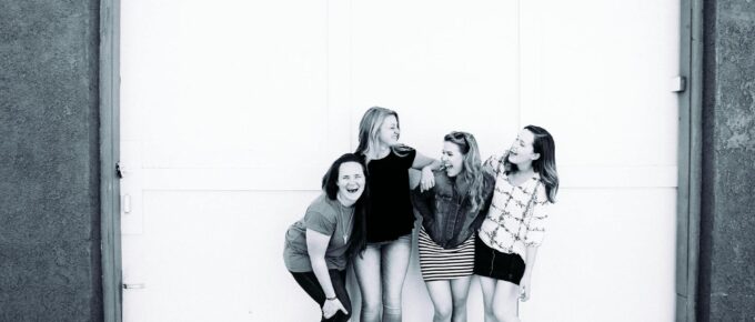 grayscale photography of four women wearing clothes