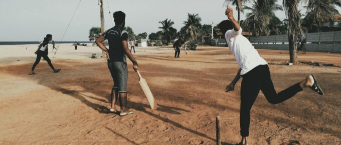 men playing cricket at beach