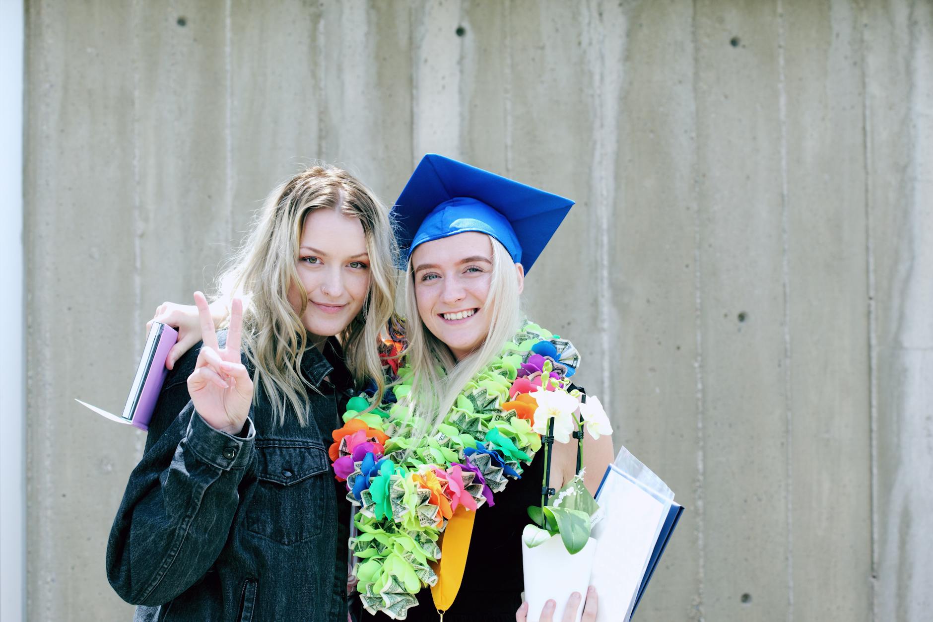 woman wearing blue mortarboard cap standing near woman wearing blue jacket