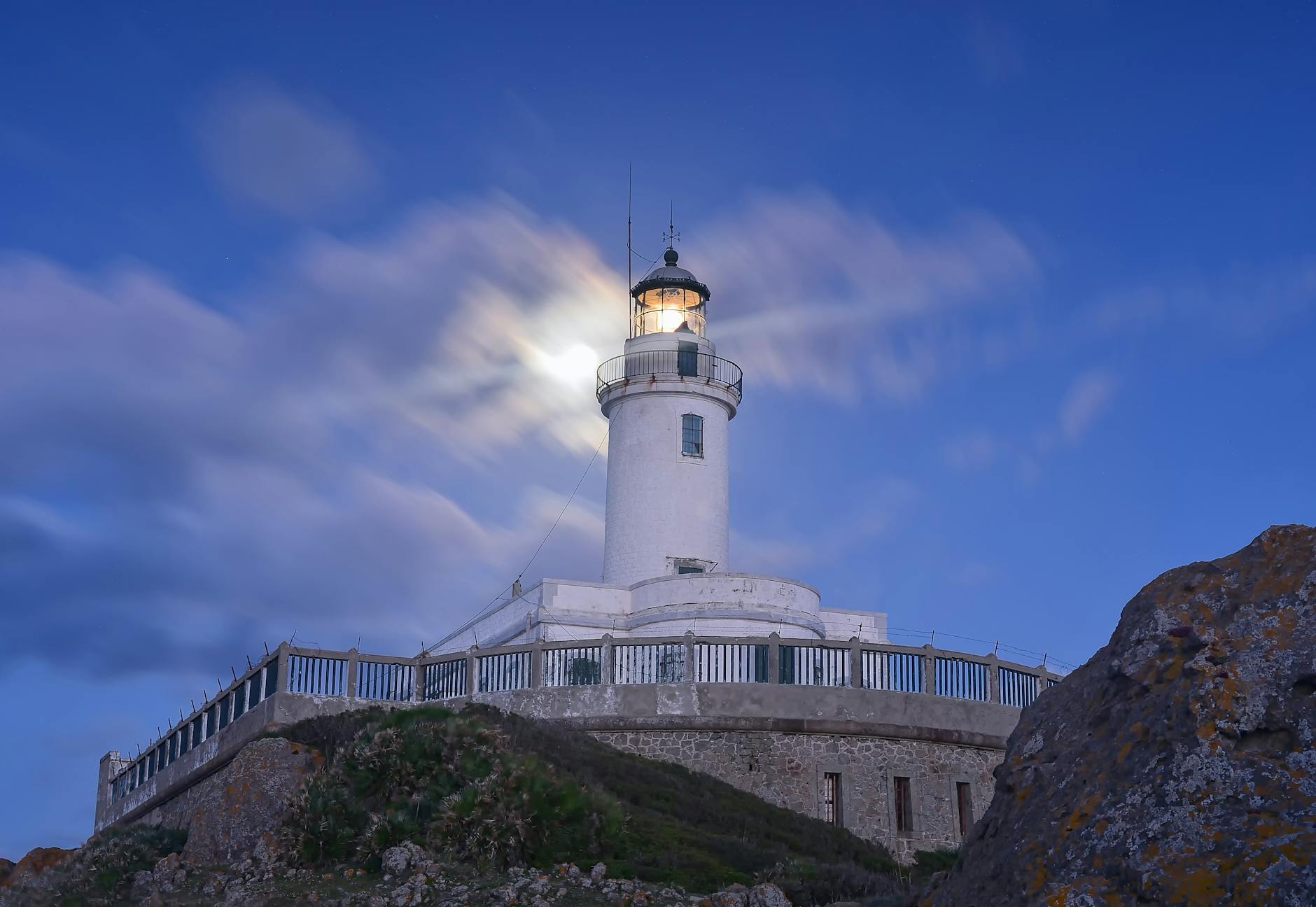 white lighthouse on rocks at dawn