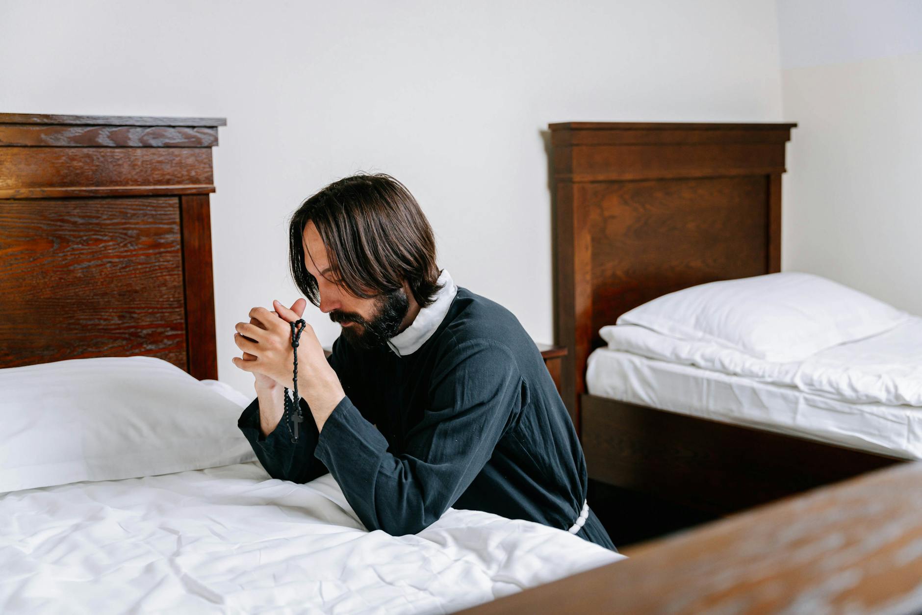 man kneeling beside a bed